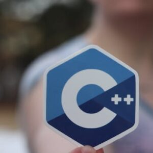 Close-up of person holding a C++ logo sticker, blurred background.