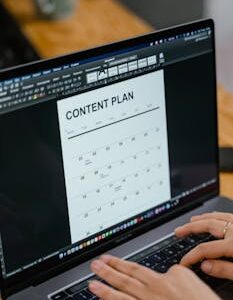 Close-up of hands typing on a laptop displaying a content plan document, ideal for business or marketing content.